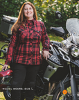 Woman in a red and black plaid SHIMA renegade motorcycle shirt standing next to a motorcycle with a helmet.