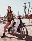 Woman sitting on a Motorcycle wearing a Black t-shirt with a woman wearing a Motorcycle helmet with the text "Wildust sister"