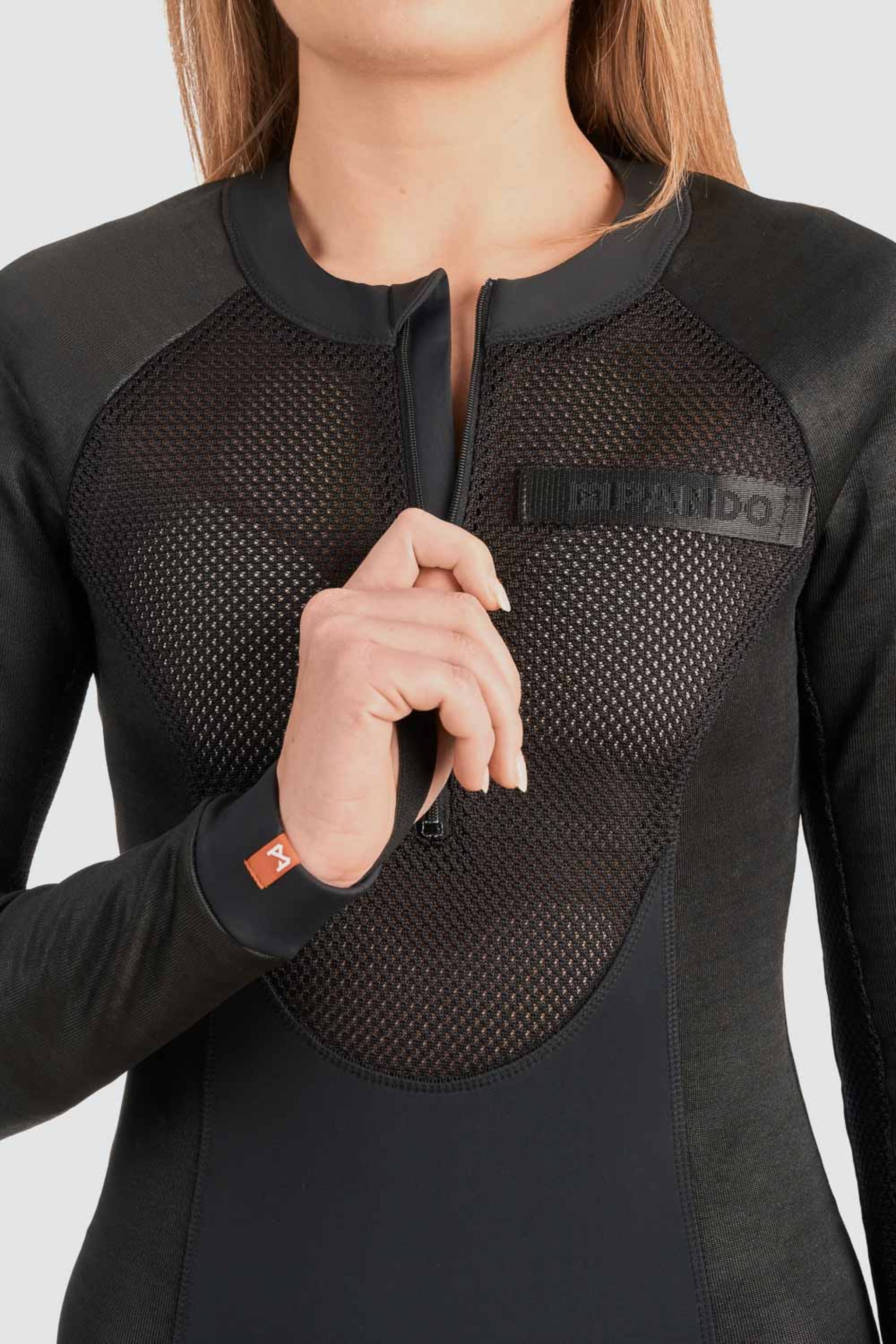 a woman unzipping the front zipper of her ventilated black body suit base layer for women from Pando
