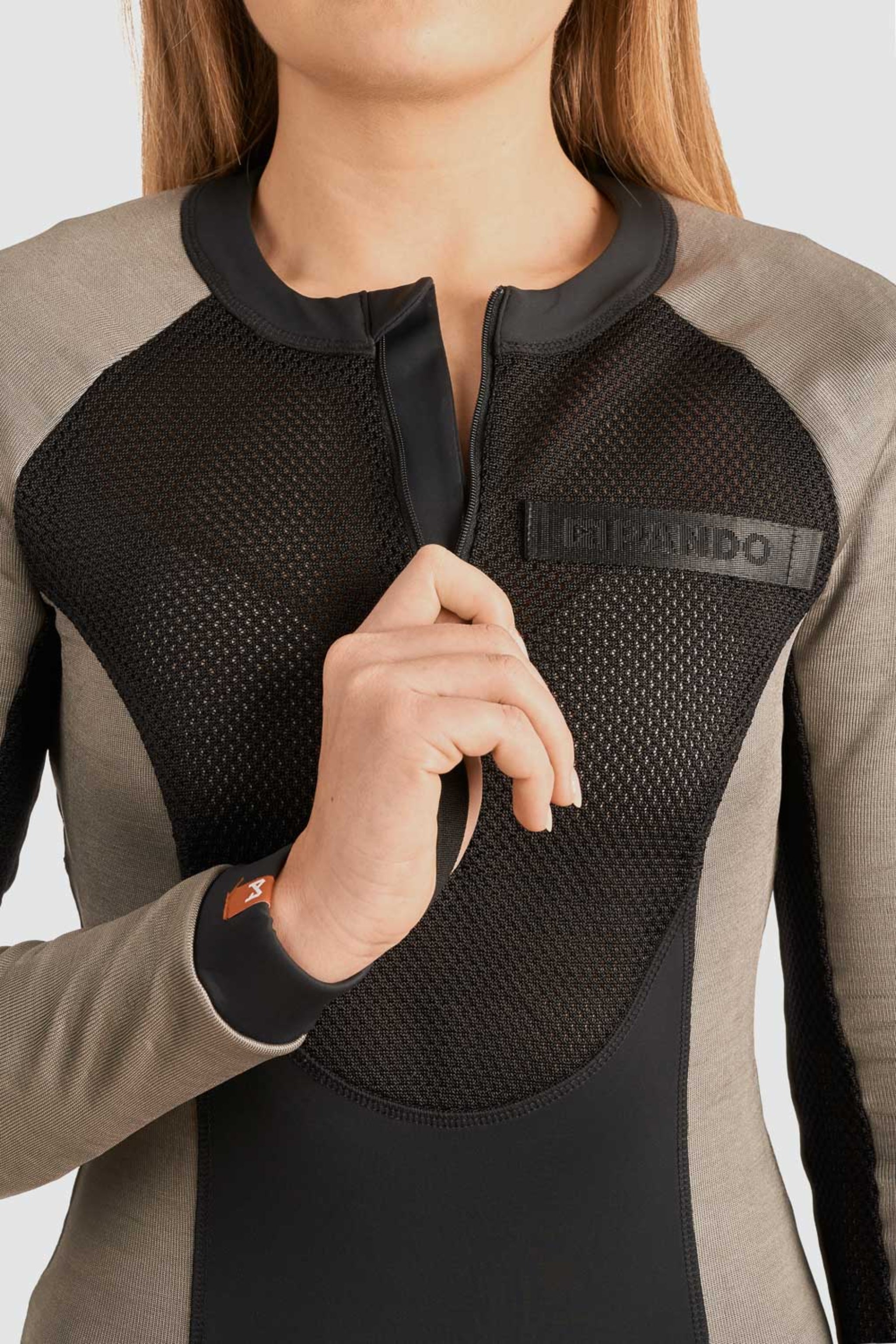 a woman unzipping front zipper of her Black and grey moto bodysuit with Pando logo