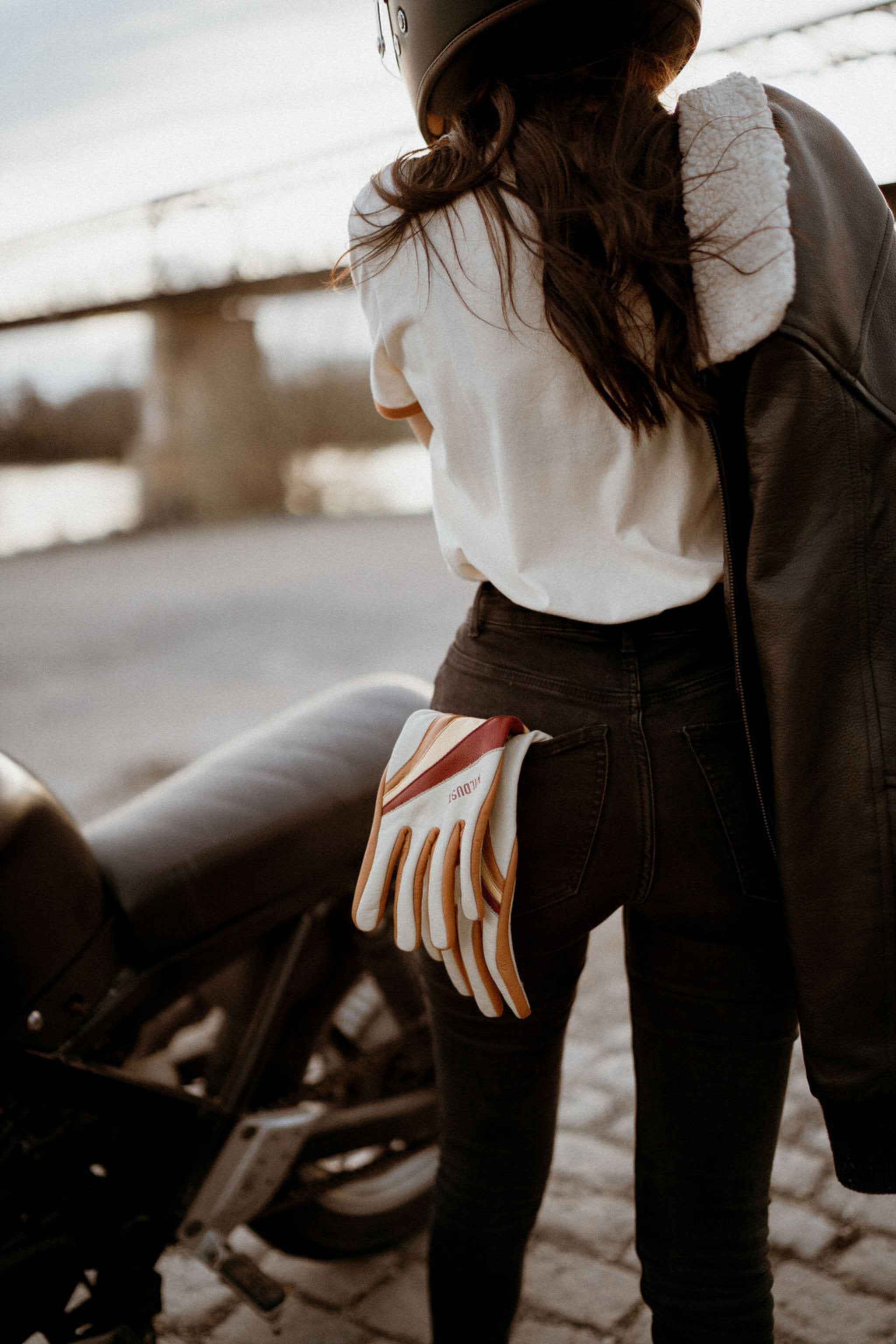 colourful leather motorcycle lady gloves from Wildust hanging from a woman's jeans back pocket