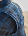 Close-up of a person wearing a blue plaid shirt with a blurred background