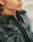 Person wearing a green plaid jacket with a blurred background