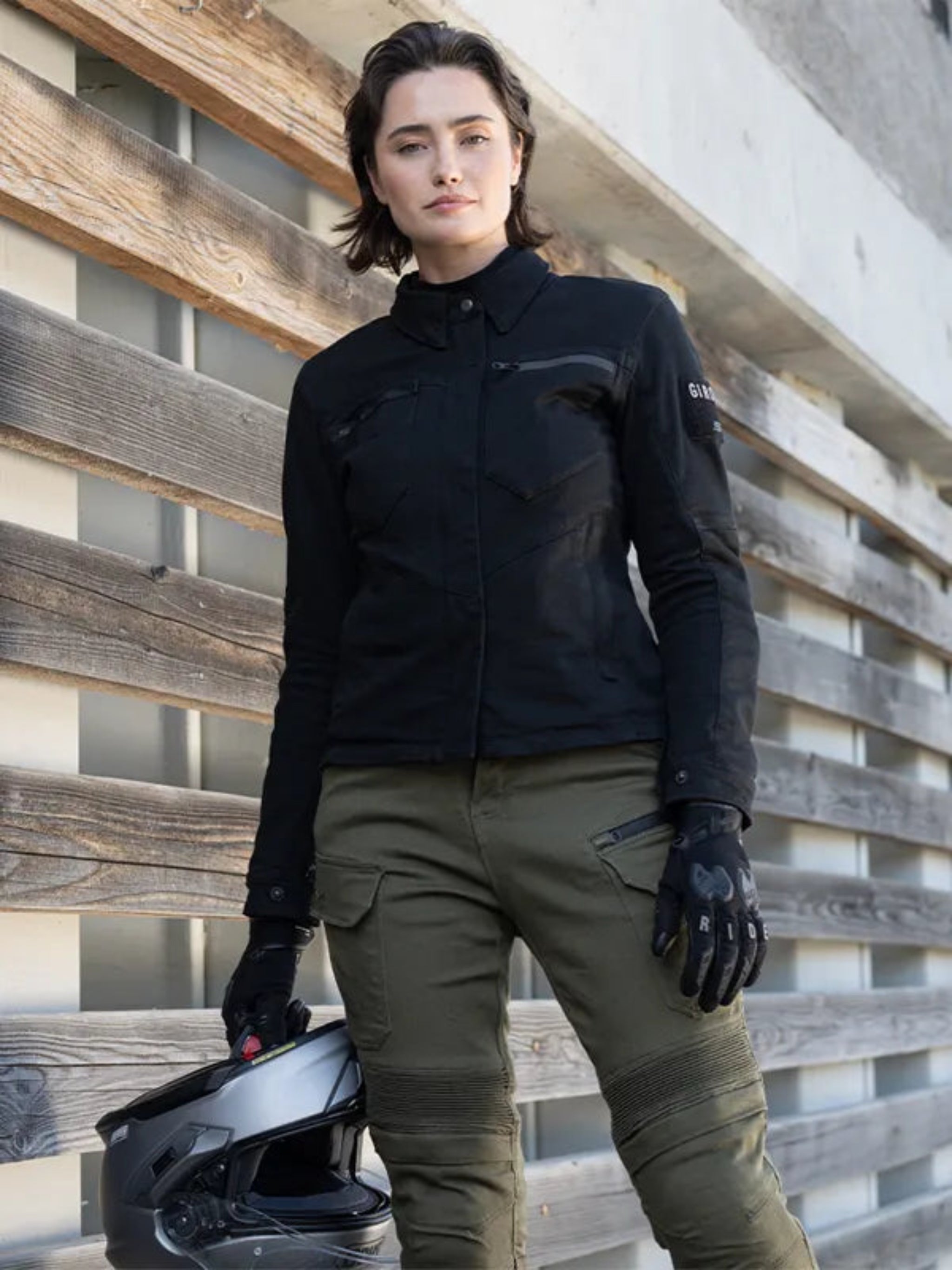 a woman wearing black shirt looking lady motorcycle jacket with front pockets and zippers and green pants