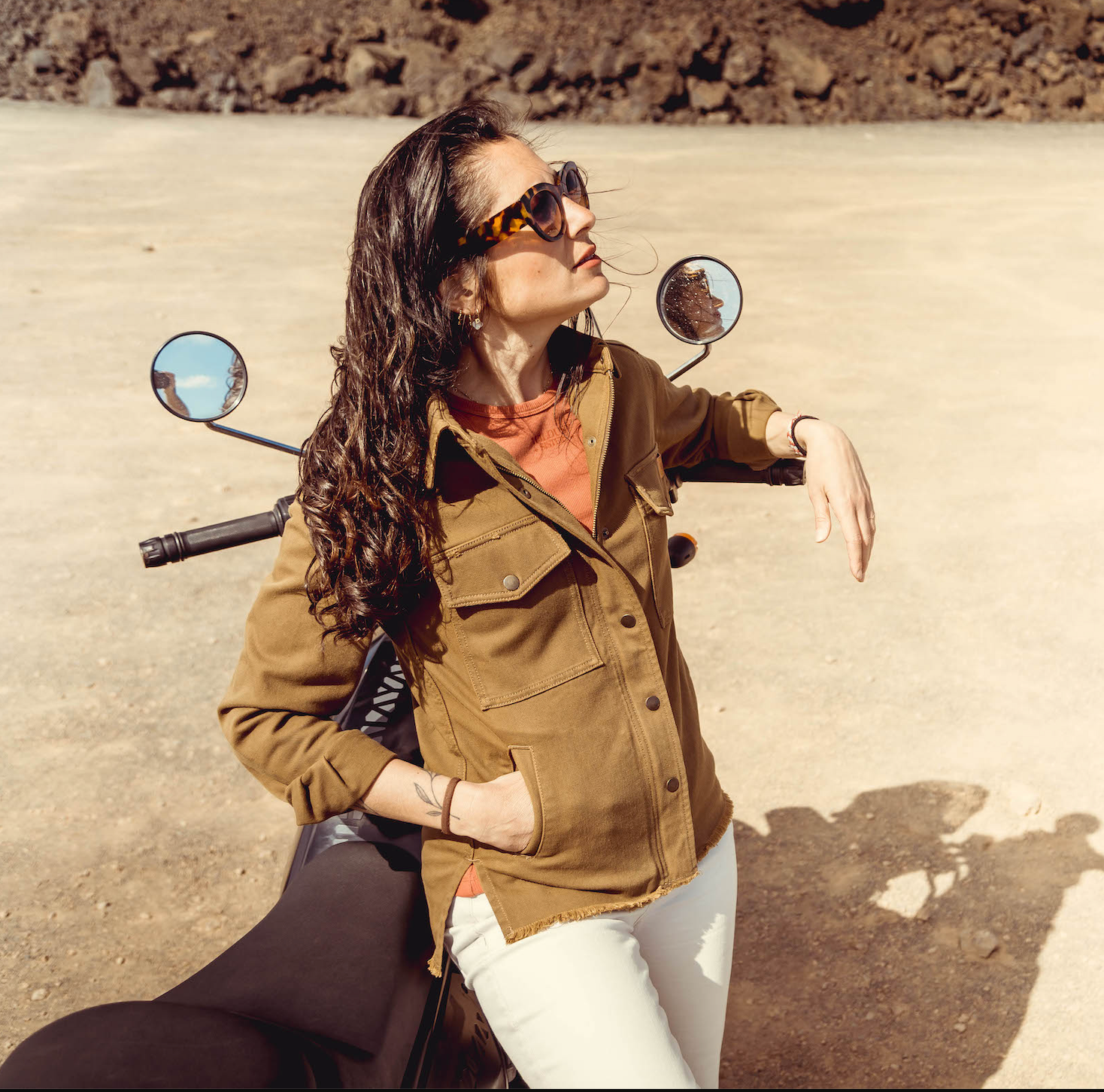a woman leaning on her motorcycle wearing brown khaki denim mc shirt