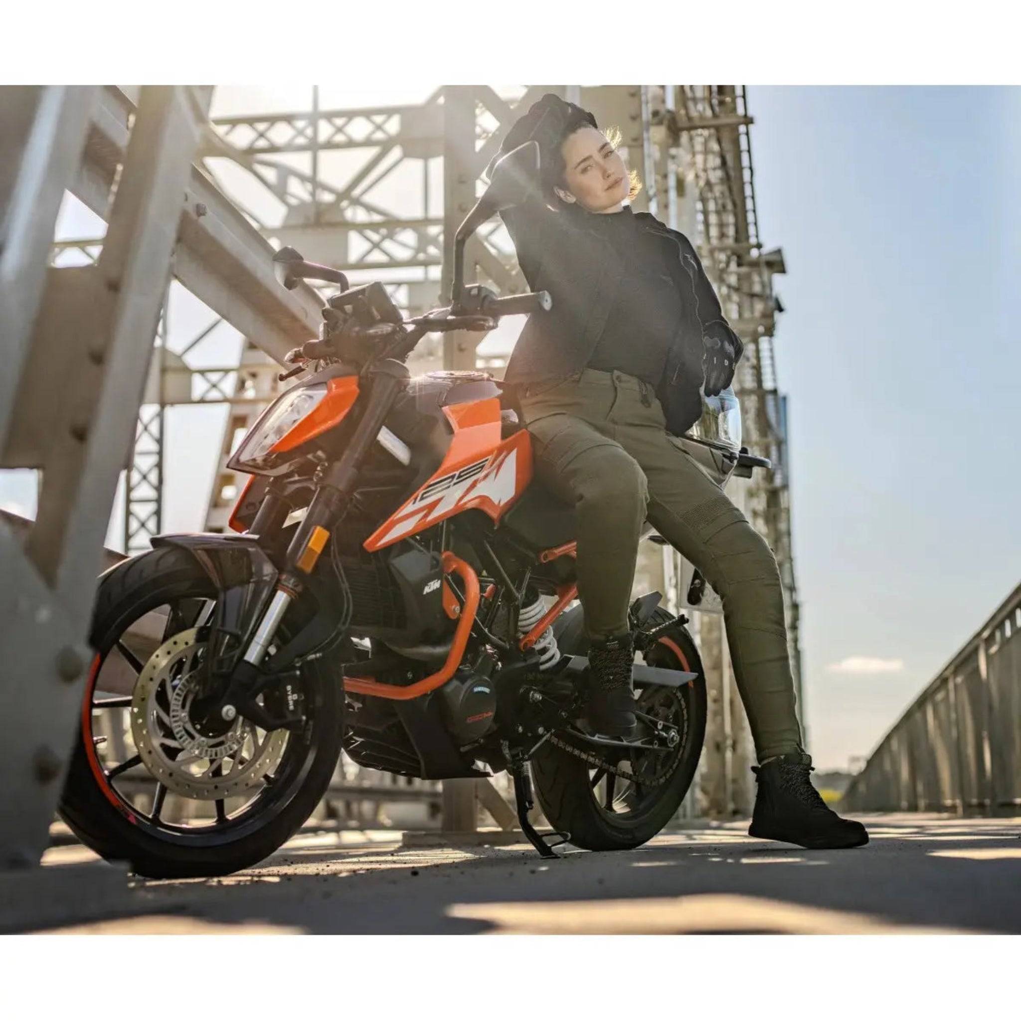 a woman on an orange motorcycle wearing black shirt looking lady motorcycle jacket