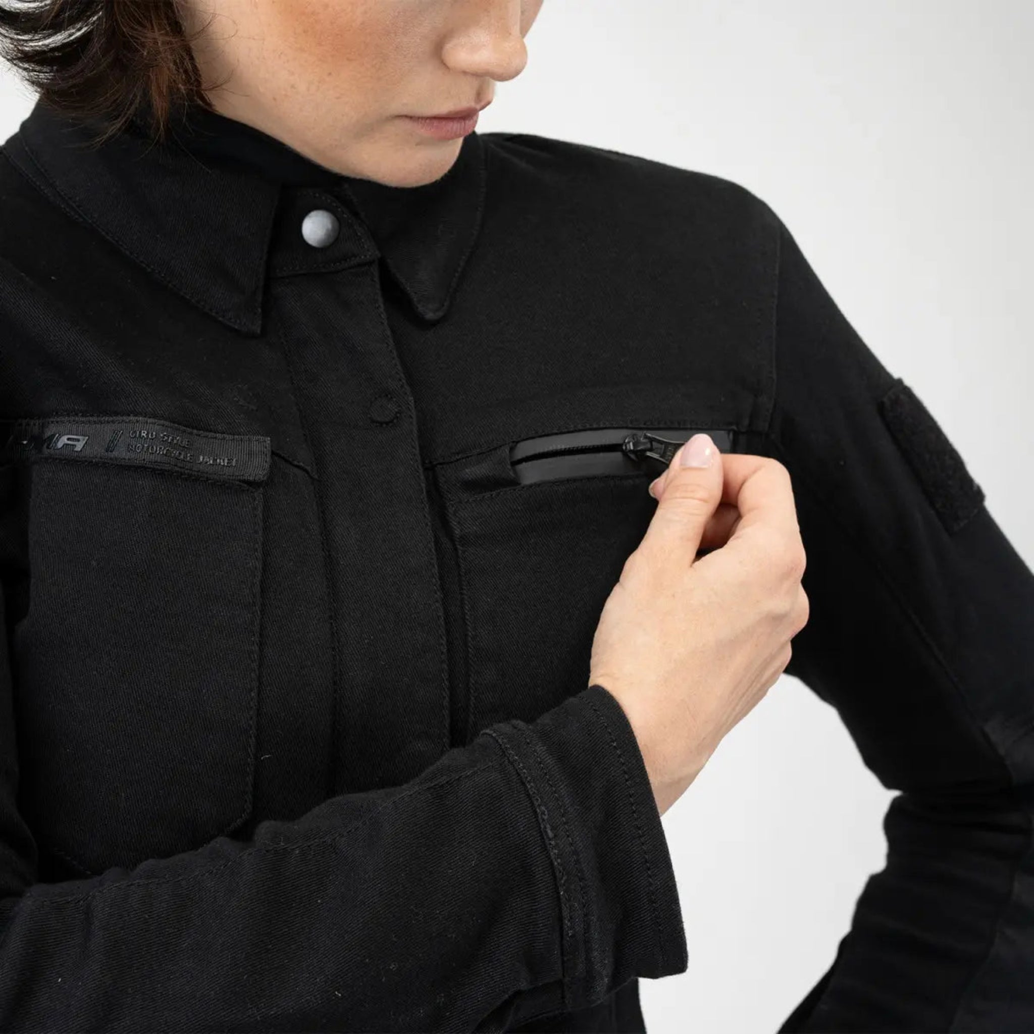 a woman zipping front pocket on her Black shirt looking lady motorcycle jacket with front pockets and zippers