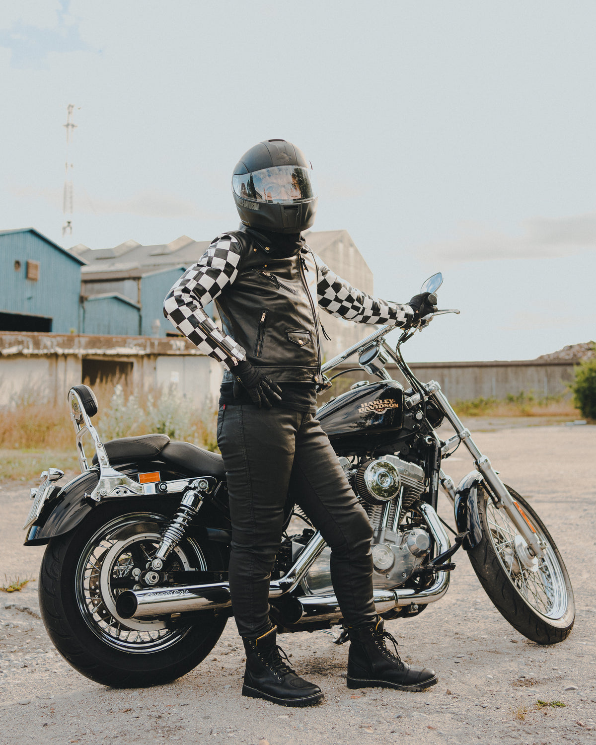 a woman wearing black motorcycle clothing standing by her motorcycle 