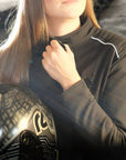 A woman closing her motorcycle jacket while holding a helmet