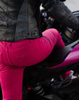 A woman wearing pink motorcycle trousers on a pink motorcycle