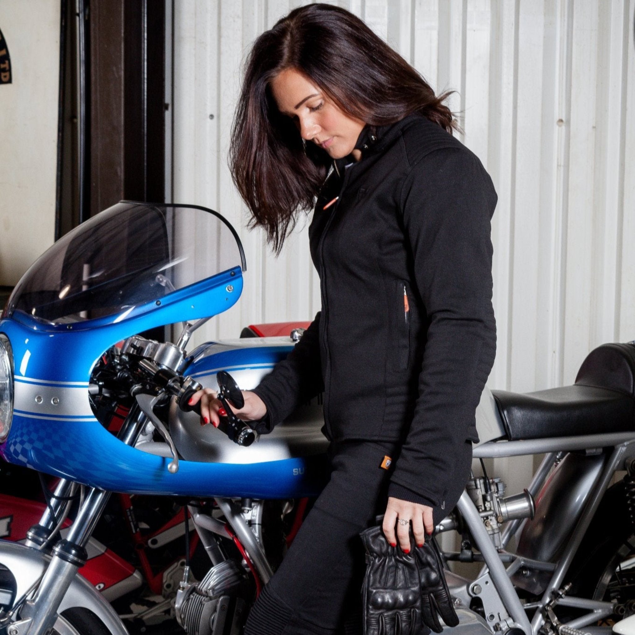 A woman standing by a motorcycle wearing women's motorcycle clothes from MotoGirl