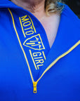 A blond woman wearing blue and yellow motorcycle hoodie