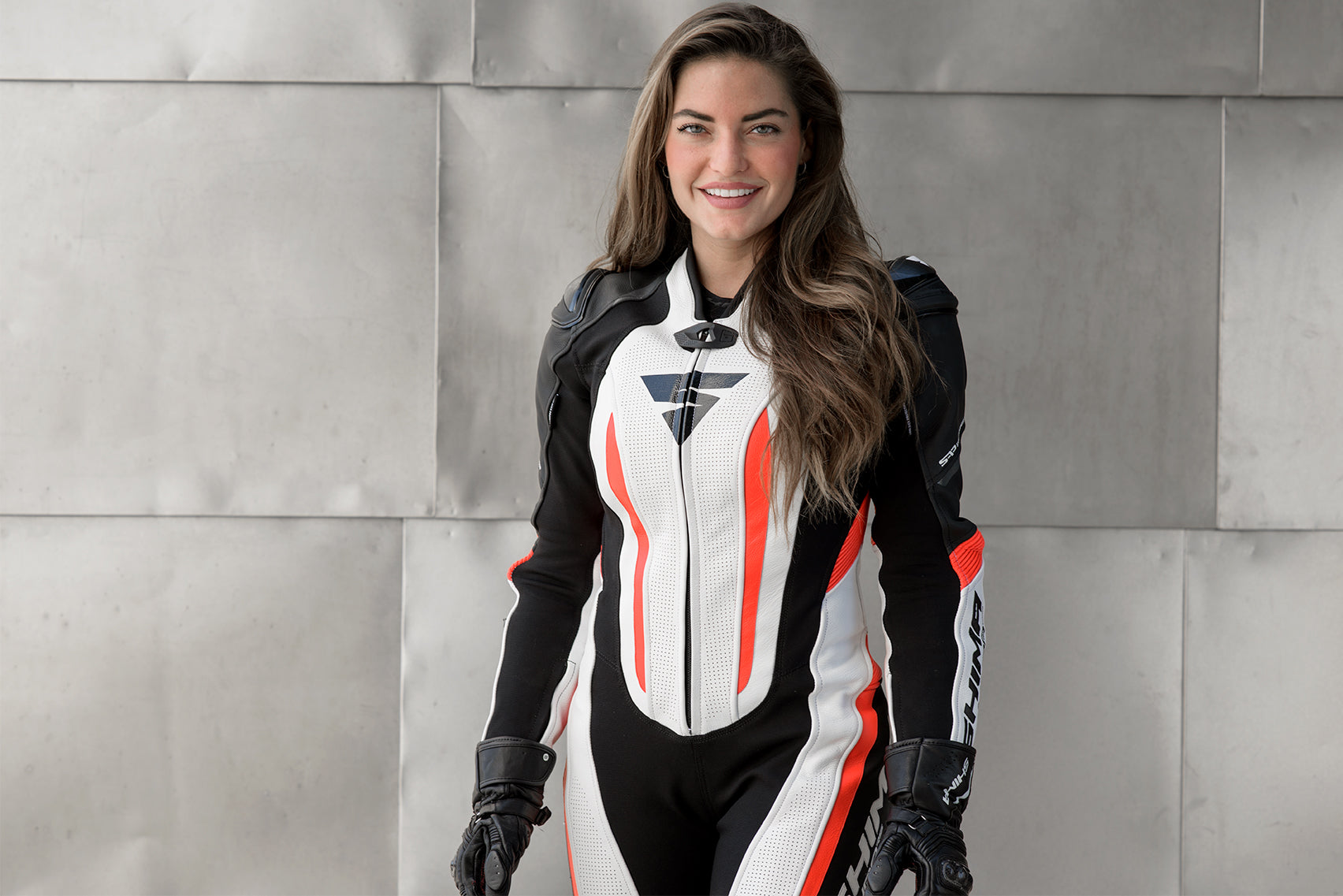A smiling woman wearing Women&#39;s racing suit MIURA RS in black, white and fluo from Shima 