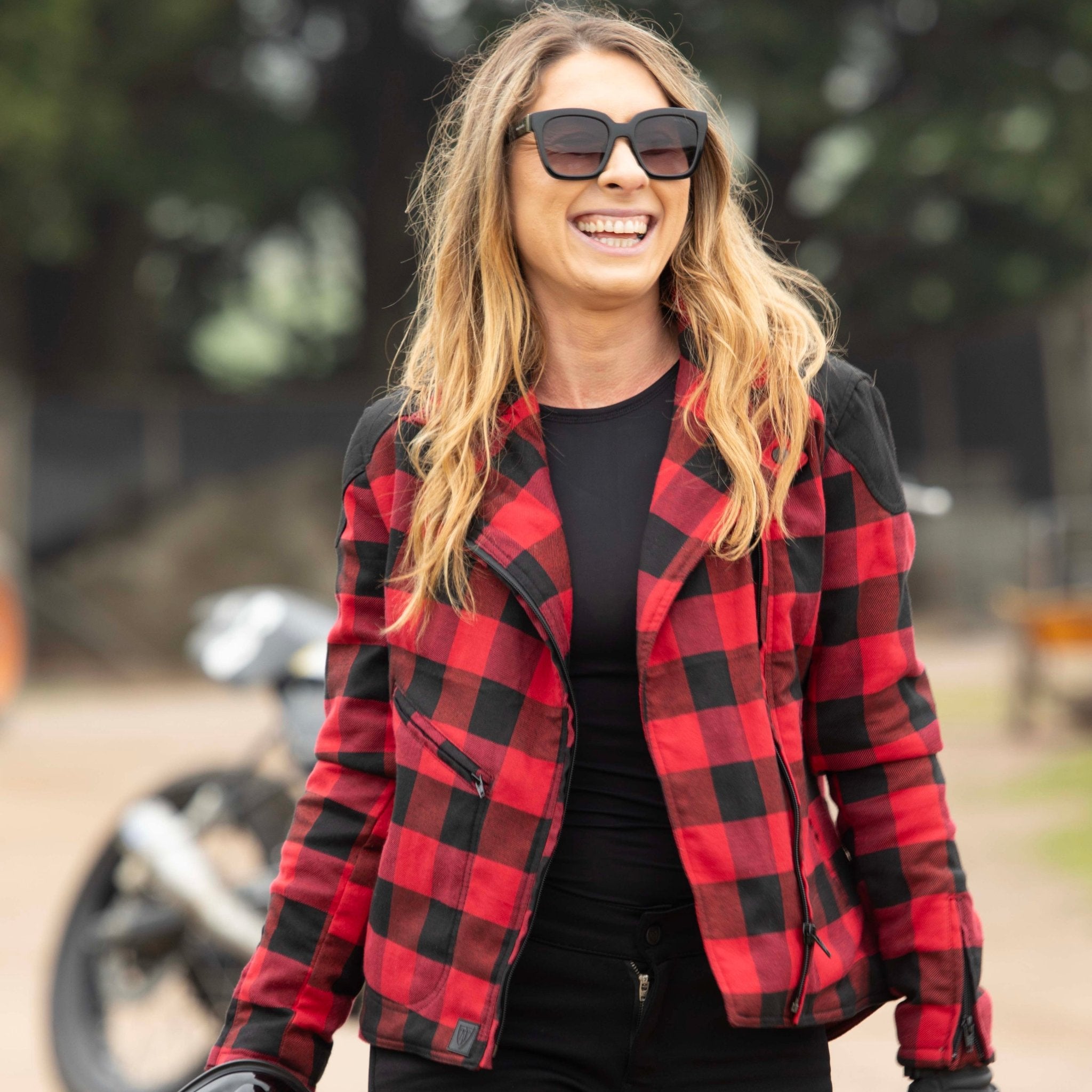 smiling woman with sunglasses wearing  red and black flannel-style women&#39;s jacket from moto girl