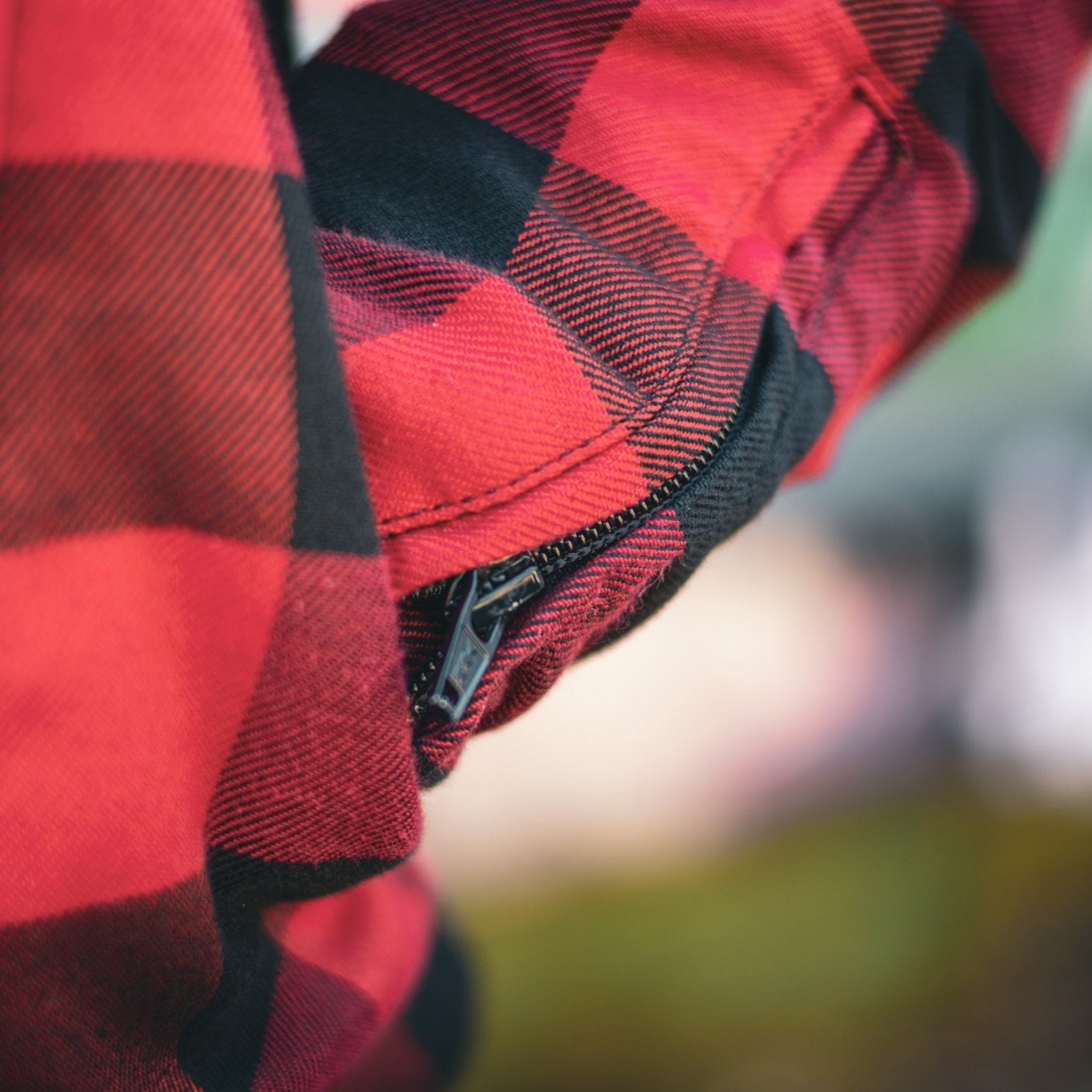 close up of sleeve with zipper detail on red and black flannel-style women&#39;s jacket from moto girl