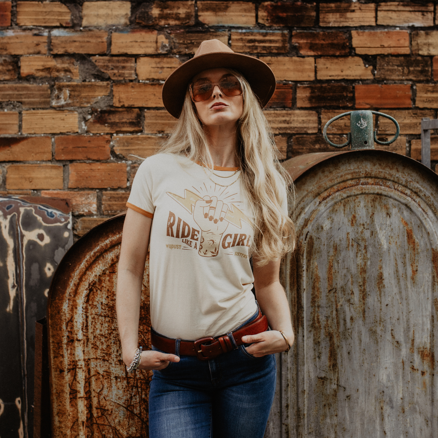 A blond woman with sunglasses and a hat wearing RIDE LIKE A GIRL retro style women&#39;s t-shirt from Wildust Sisters