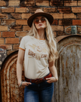 A blond woman with sunglasses and a hat wearing RIDE LIKE A GIRL retro style women's t-shirt from Wildust Sisters