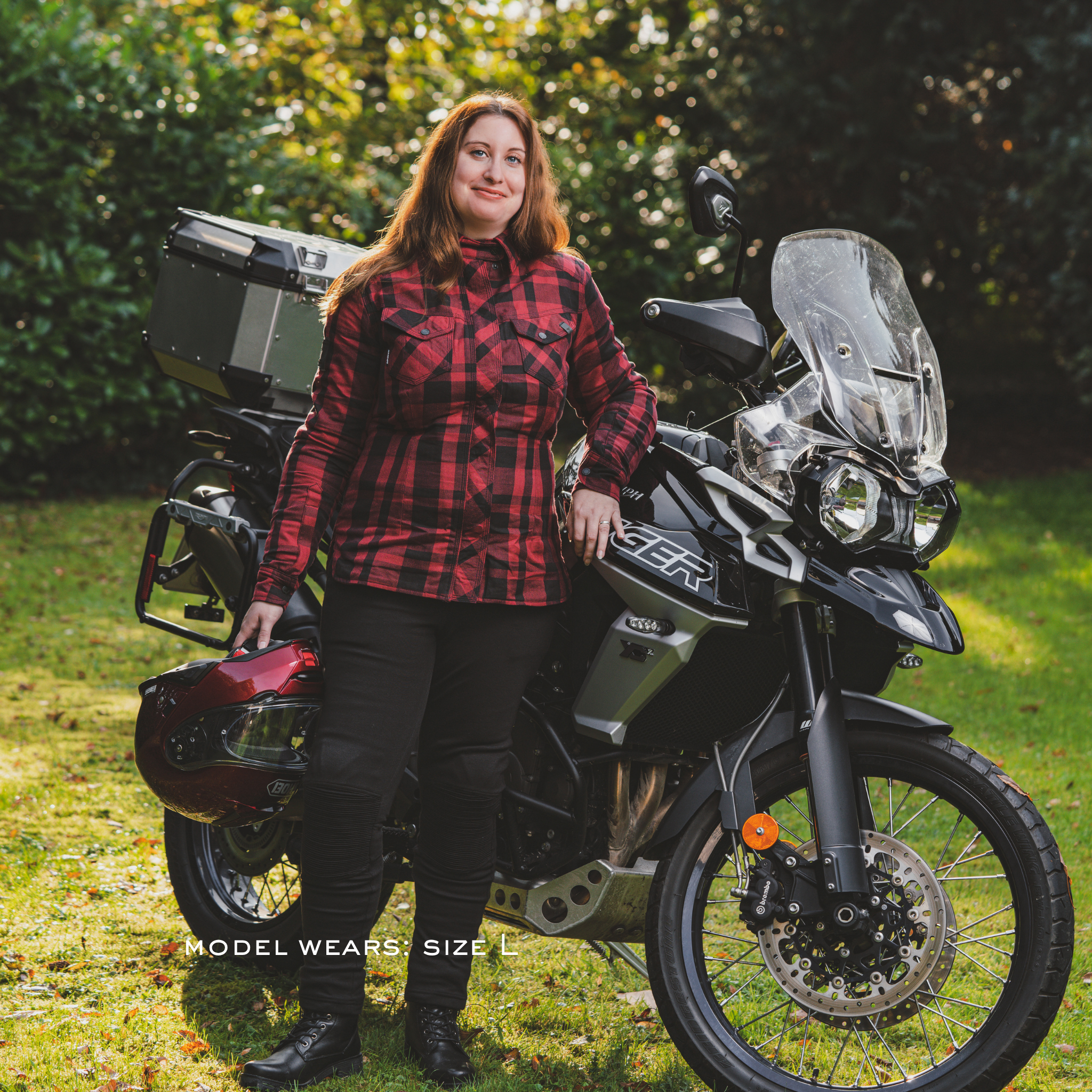 Person wearing a red plaid SHIMA RENEGADE motorcycle shirt standing next to a motorcycle in an outdoor setting