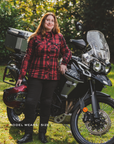 Person wearing a red plaid SHIMA RENEGADE motorcycle shirt standing next to a motorcycle in an outdoor setting
