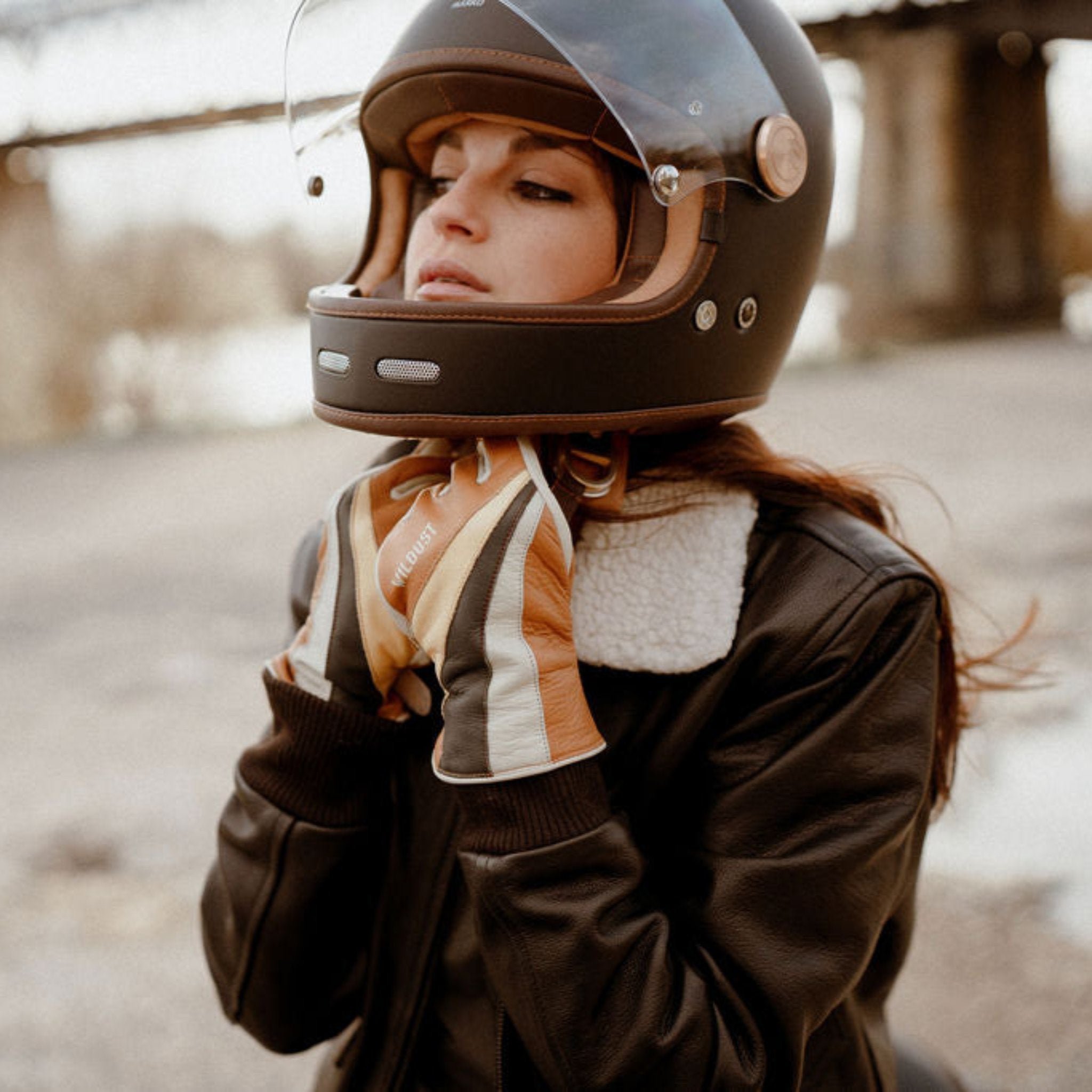 a woman closing her helmet waring colourful leather gloves from WILDUST