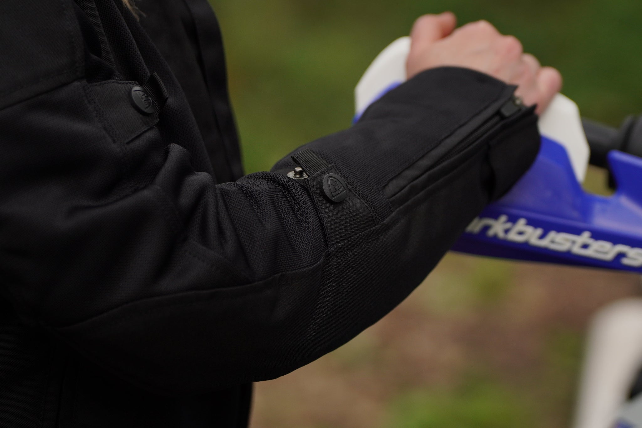 a close up of a woman&#39;s hand on a motorcycle mirror showcasing the sleeve of her black mesh jacket