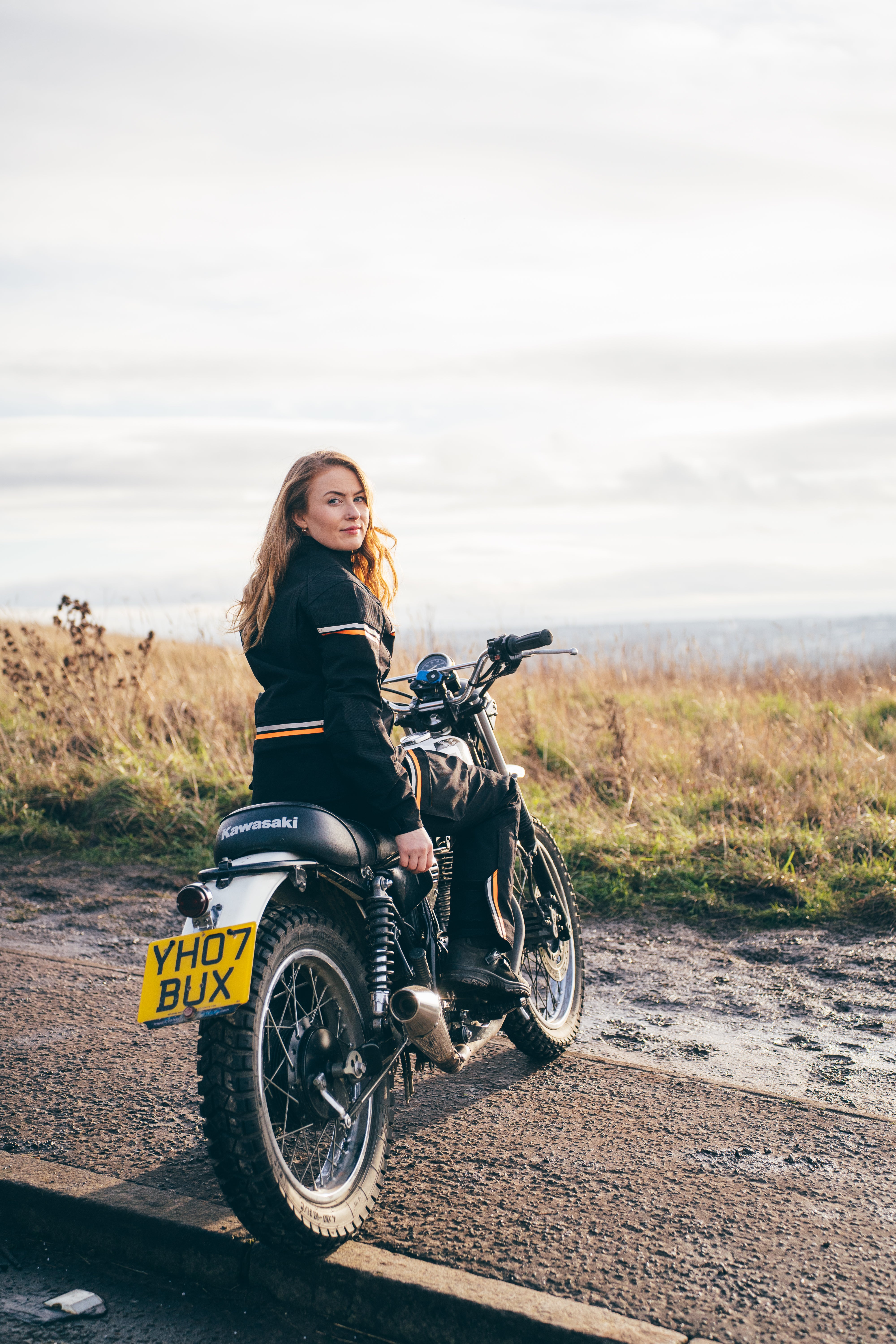 a women on a motorcycle with black textile suit with orange black details 