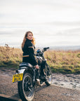 a women on a motorcycle with black textile suit with orange black details 