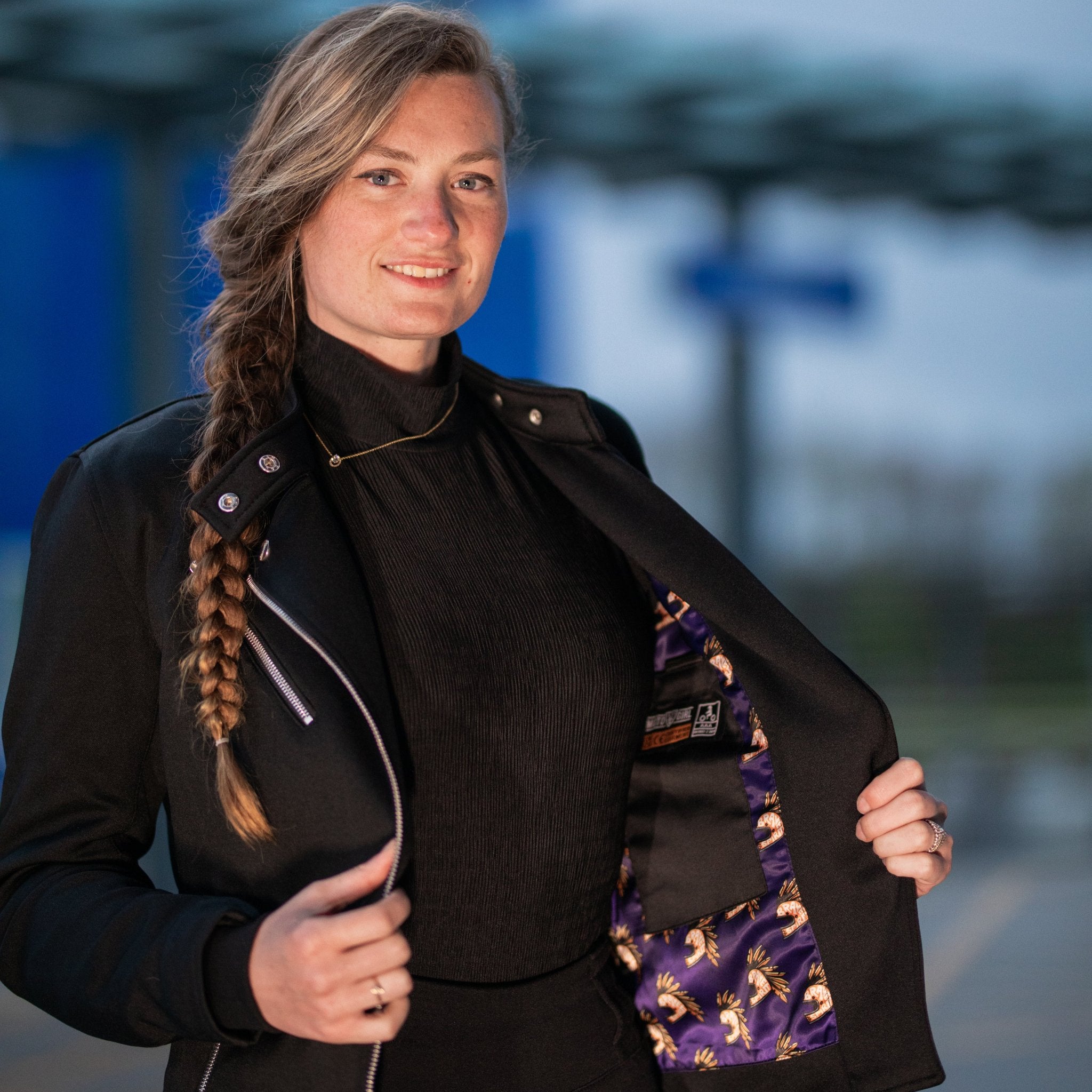 a young woman opening her Black retro style woman&#39;s motorcycle jacket with silver zip details