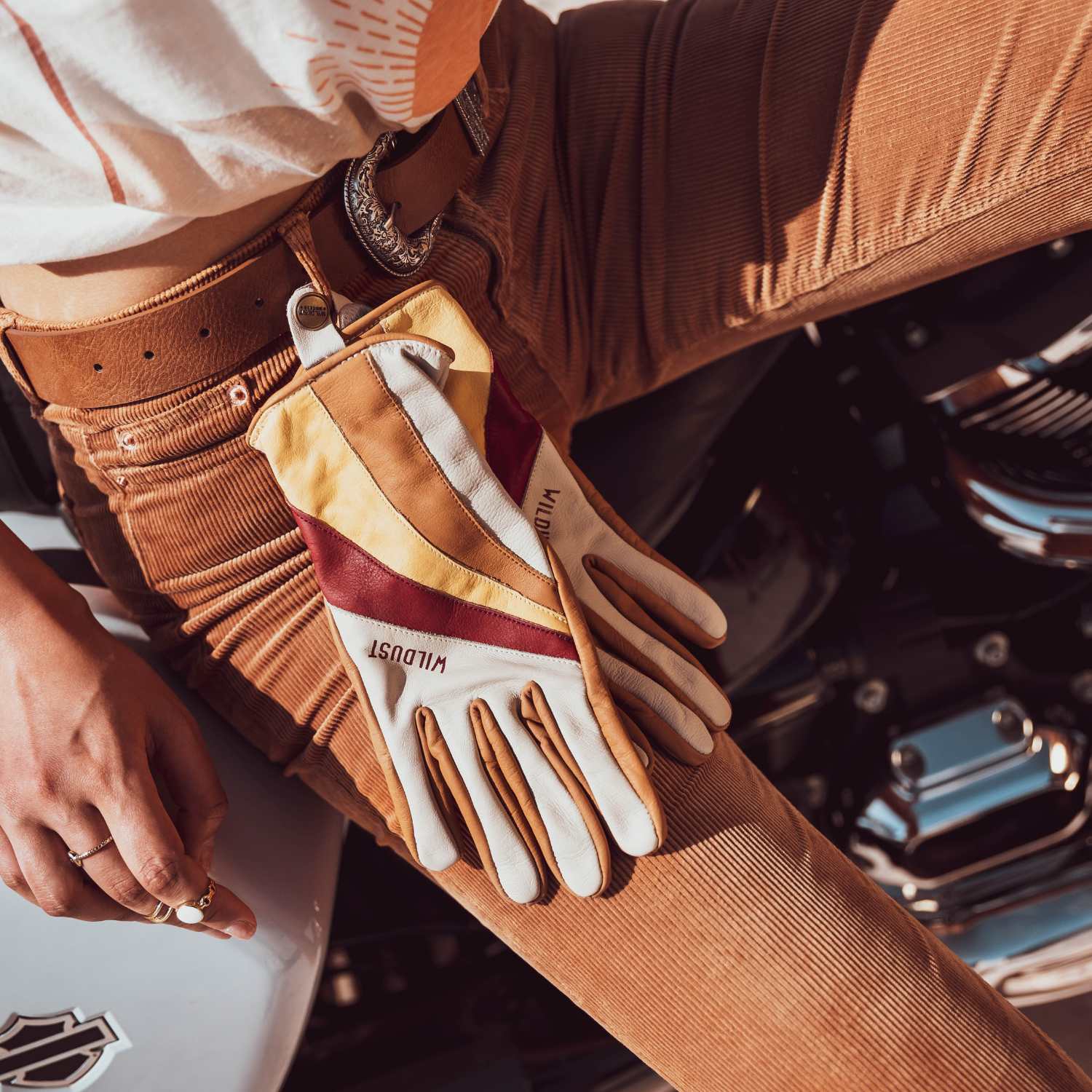 colourful leather motorcycle lady gloves from Wildust hanging from the woman&#39;s belt