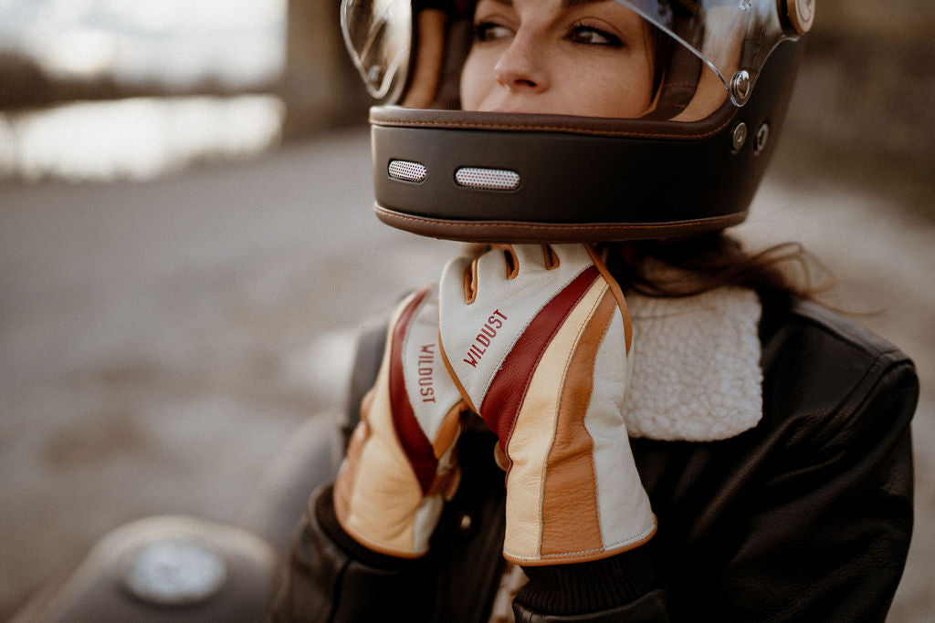 a woman closing her motorcycle helmet wearing colourful leather motorcycle lady gloves from Wildust