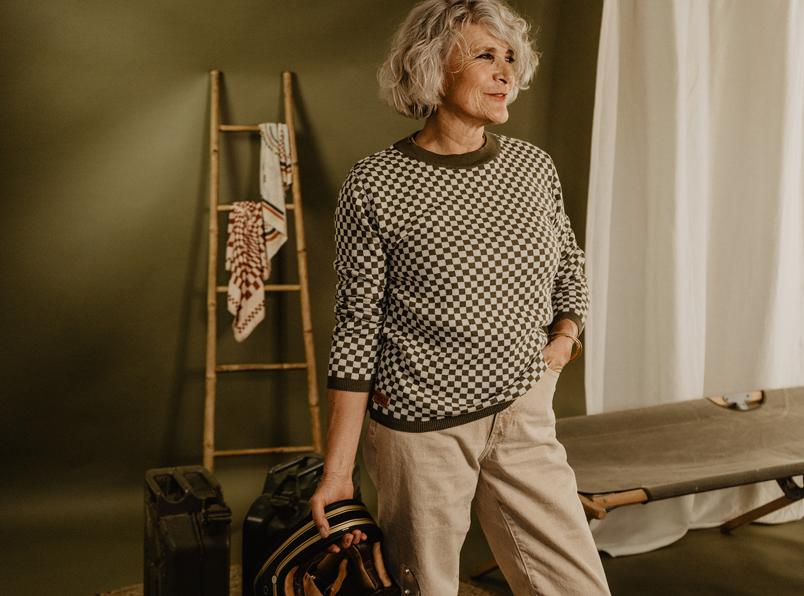 an older lady wearing a knitted khaki green and white jumper with chessboard motives  from Wildust