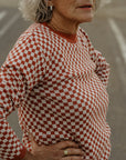 an older lady wearing a knitted red and white jumper with chessboard motives from Wildust