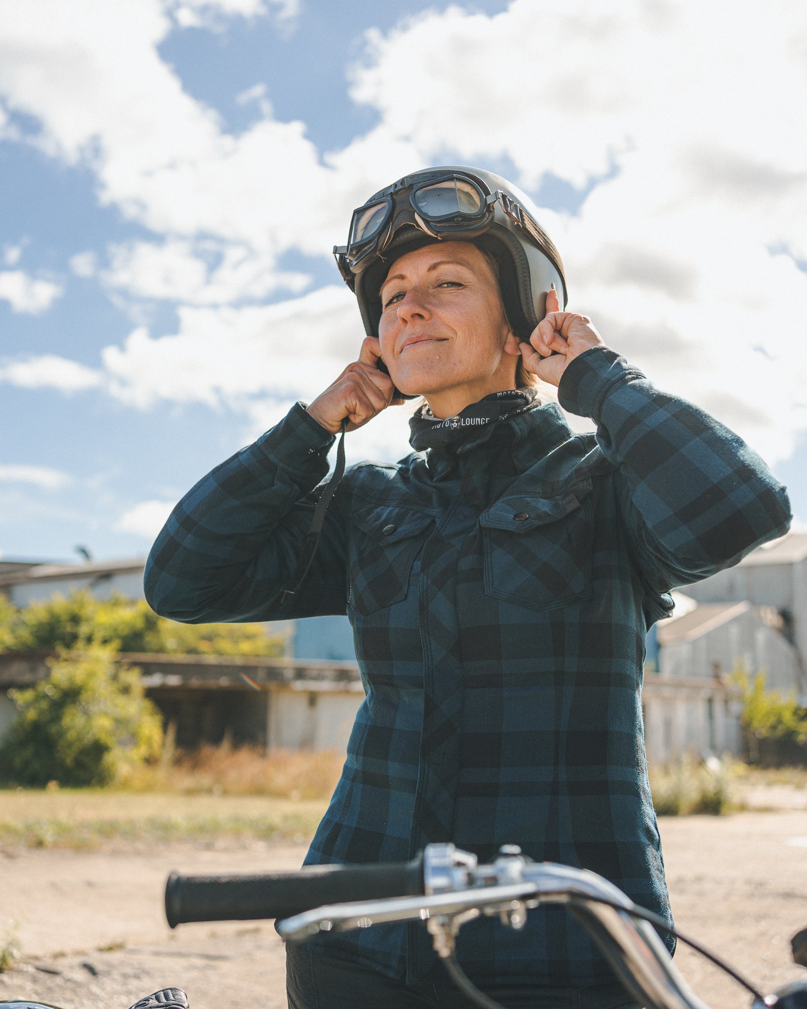 A woman putting on her motorcycle helmet