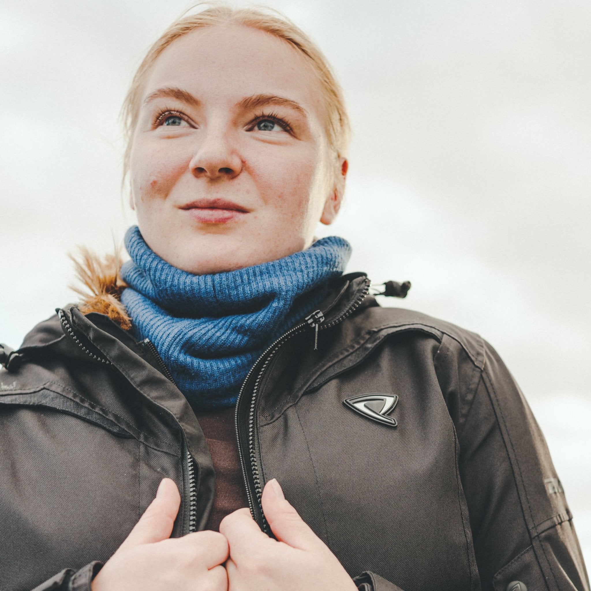 Close-up of a light red-haired woman wearing a blue knitted neck warmer from Moto Girl.