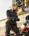 A blong young woman standing by her motorcycle wearing Black and grey lumberjack style women's motorcycle shirt from Shima 