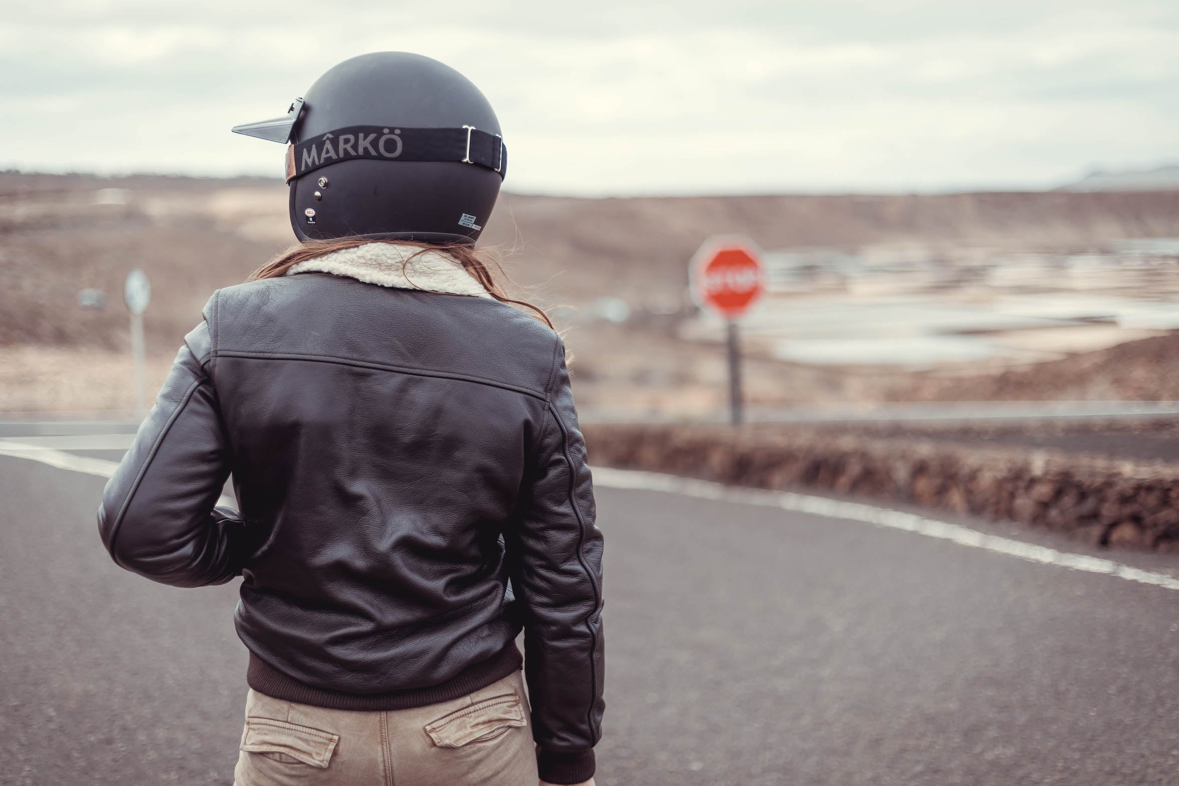 a back of woman motorcyclists wearing brown aviator style jacket