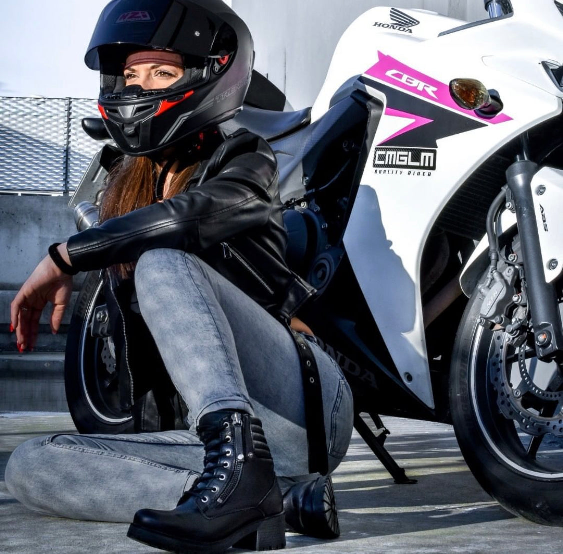 a woman by her sports bike wearing black leather motorcycle boot 