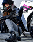 a woman by her sports bike wearing black leather motorcycle boot 