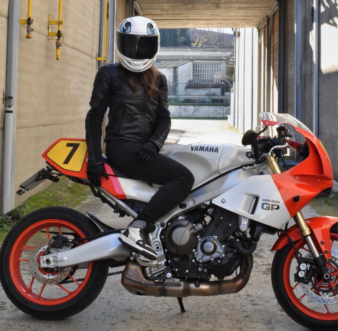 Person sitting on a Yamaha motorcycle wearing a helmet in an outdoor setting.