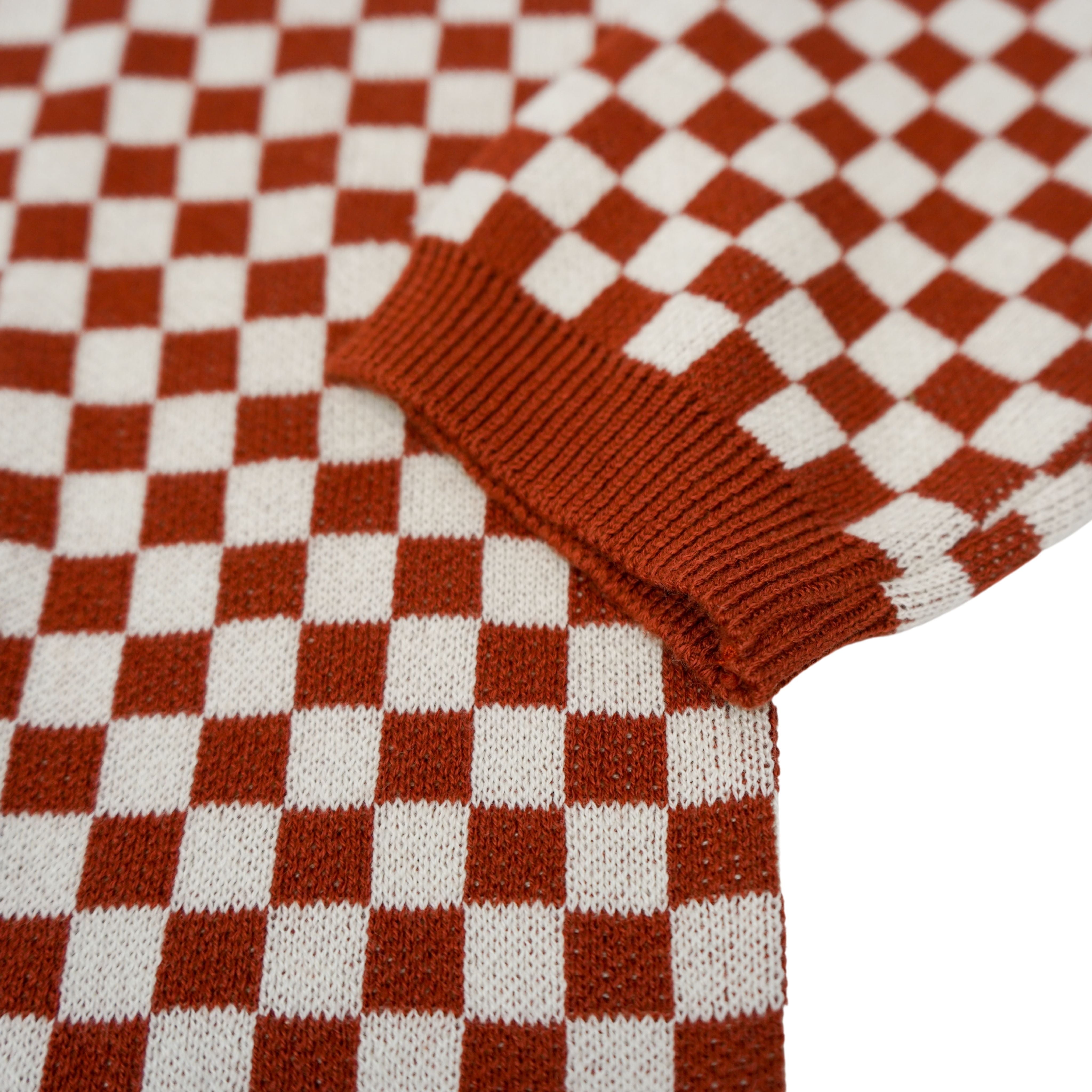 a sleeve of a knitted red and white jumper with chessboard motives from Wildust