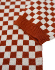 a sleeve of a knitted red and white jumper with chessboard motives from Wildust