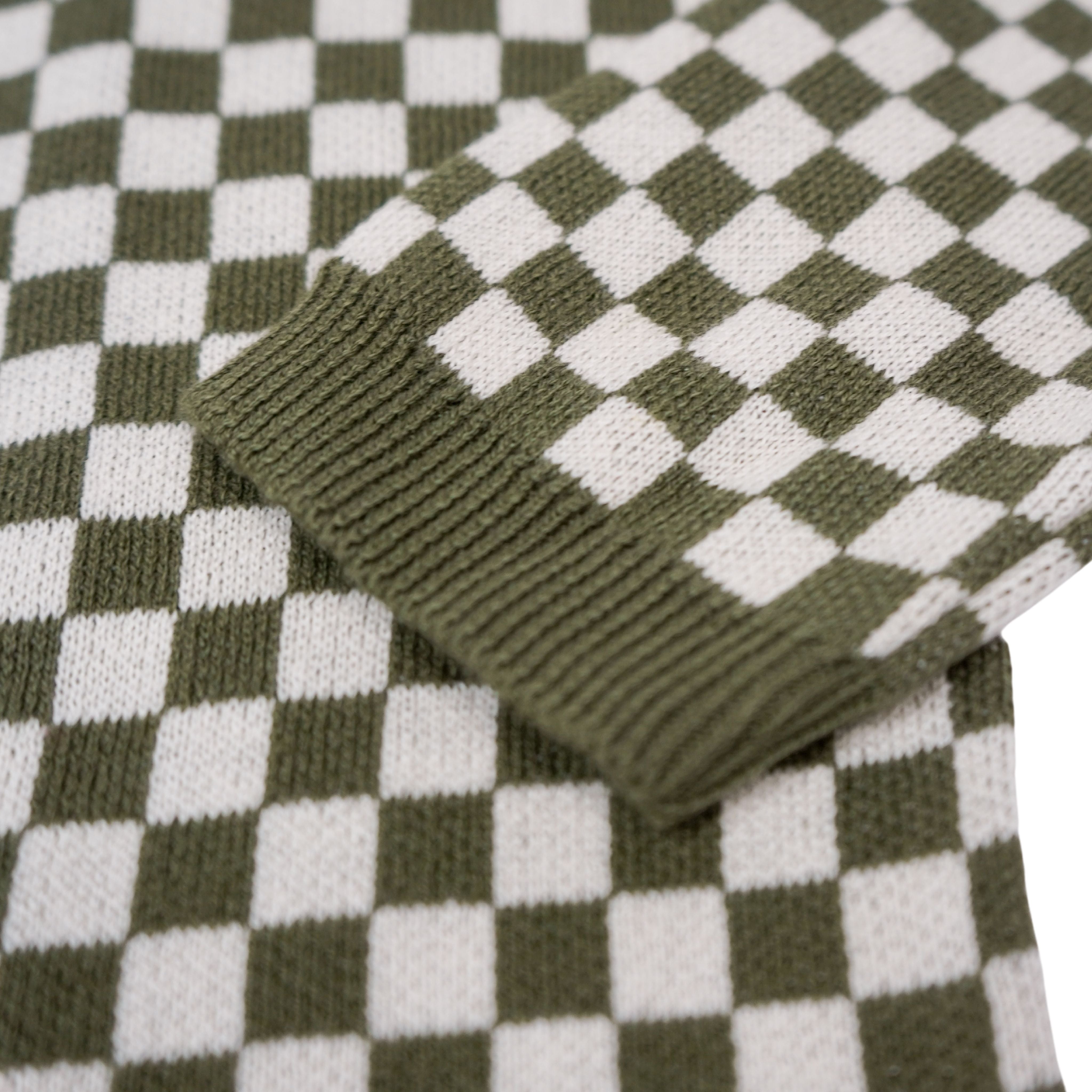 a sleeve of a knitted khaki green and white jumper with chessboard motives  from Wildust