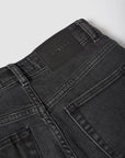 Close-up of black jeans with a brand label on a light gray background