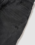 Close-up of black jeans with a brand logo on a white background