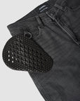 Black textured shoe insert on a pair of black jeans with a visible brand label.