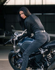 A woman sitting on a motorcycle with airplanes in the background