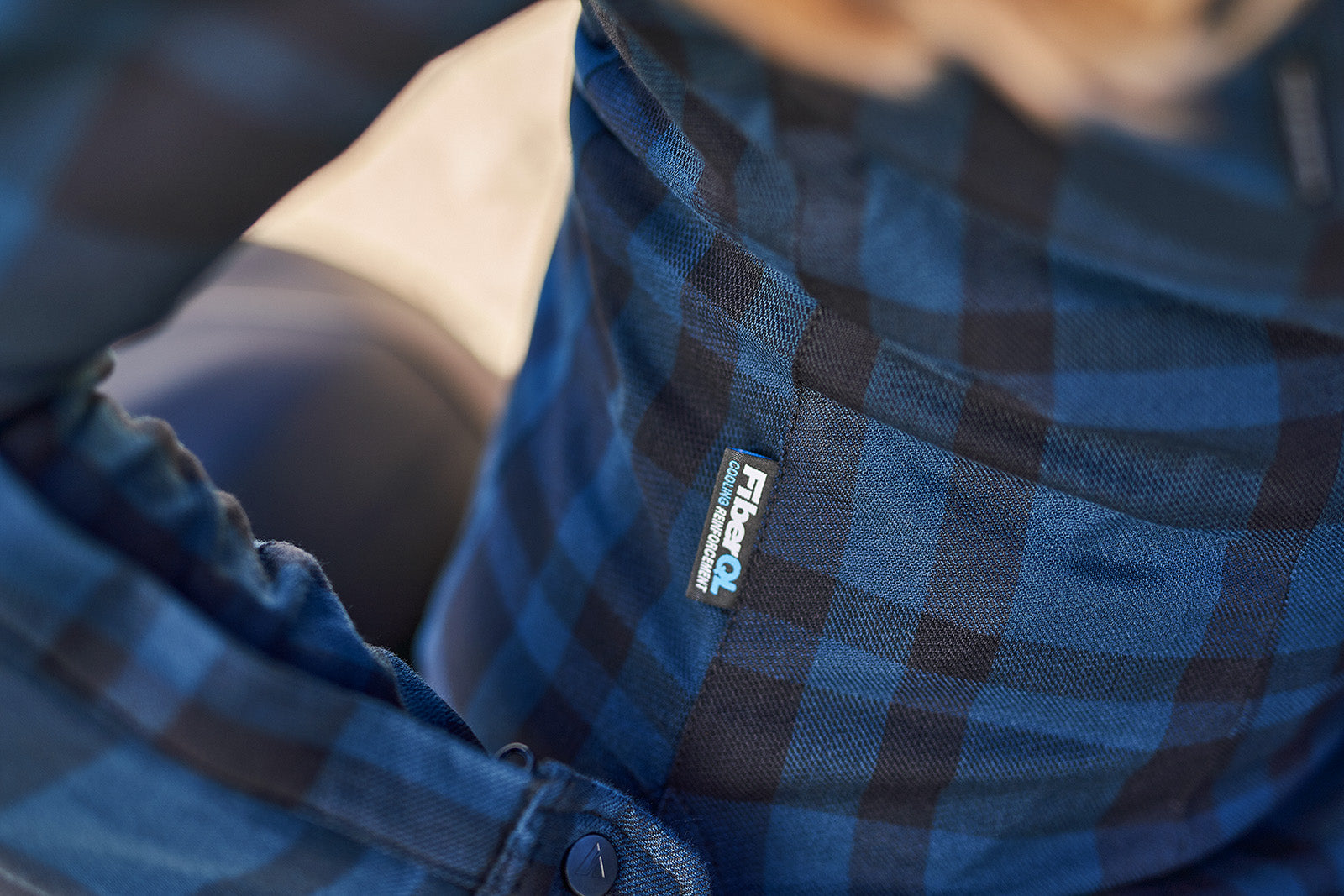 Close-up of a blue plaid shirt with a visible brand logo.