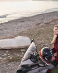 Woman sitting on a Ducati scooter by a beach