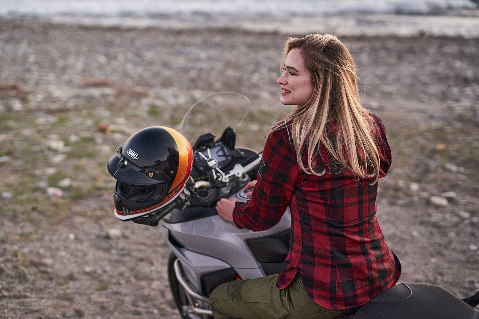 Woman sitting on a motorcycle with a helmet on a beach