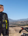 A woman standing by her mc wearing shima motorcycle touring jacket for women in black/ fluo